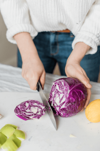 woman's hands holding a knife and cutting radish